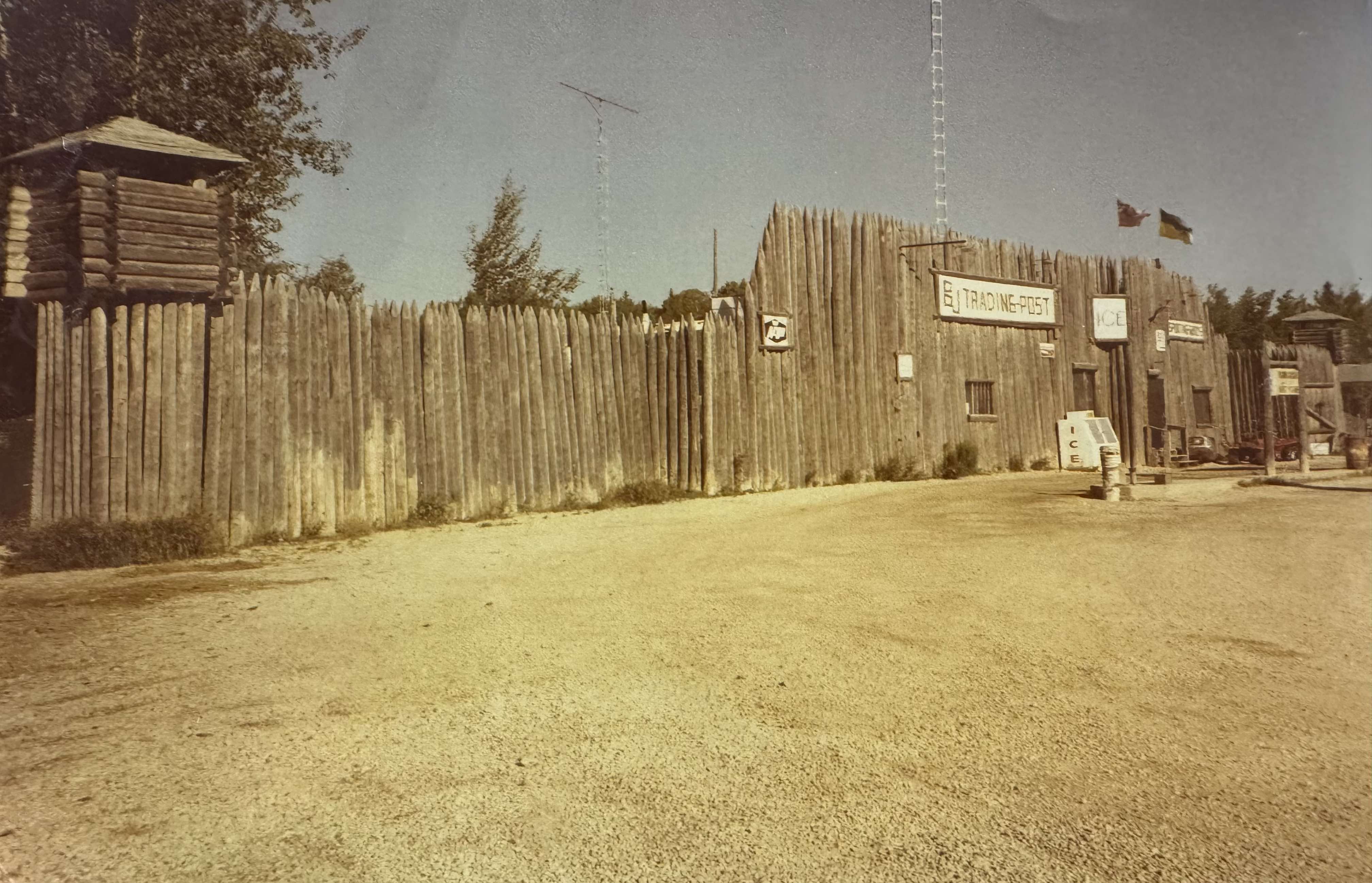 Vintage 1980s photo of BJ’s Trading Post in Wanless, Manitoba, featuring a fort-like wooden structure with a lookout tower and store signs.