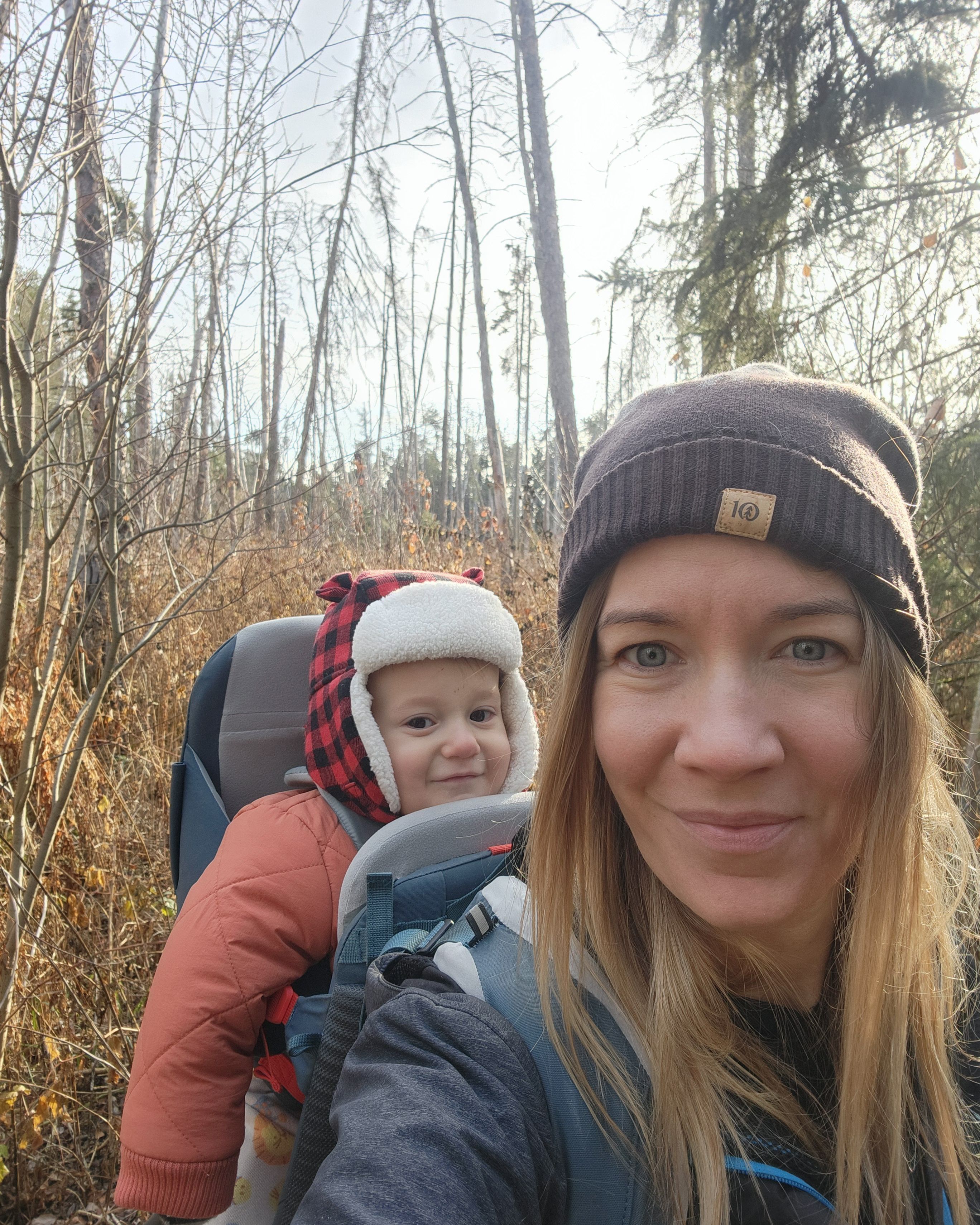 Meagan with her very happy baby in a pack on her back while hiking in the fall