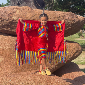 happy girl wearing brightly coloured regalia with shawl