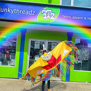 image of store front with Indigenous dancer performing outside on sidewalk