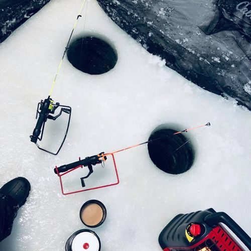 Ice fishing holes and coffee inside pop-up tent on the lake.