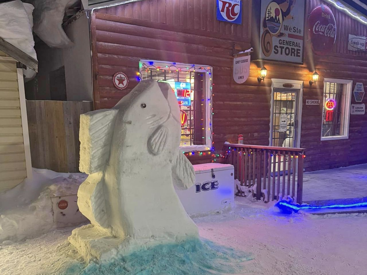 Fish snow sculpture coming up from the ground in front of the store to celebrate Trappers' Festival 2025